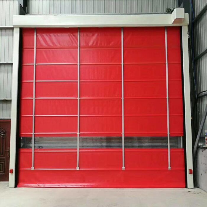Large red industrial roll-up door closed inside a warehouse, framed by light-colored steel supports and vertical tracks.