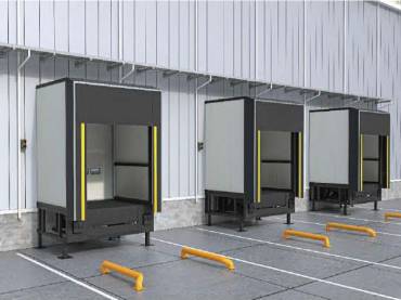 Three loading dock bays at a warehouse with open shelters, yellow safety bollards, and concrete ramps for shipping and receiving.