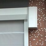Close-up of a white window frame against a brown mosaic tile wall.
