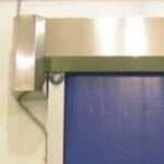 Close-up of a blue metal door with a steel frame and a silver support bracket on the left side.